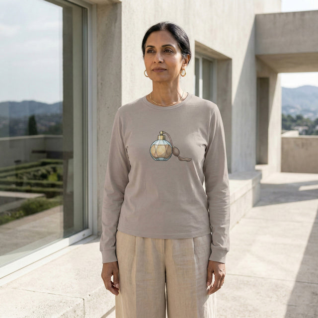 Woman wearing a beige long-sleeve shirt with a graphic design, standing in front of a modern building.