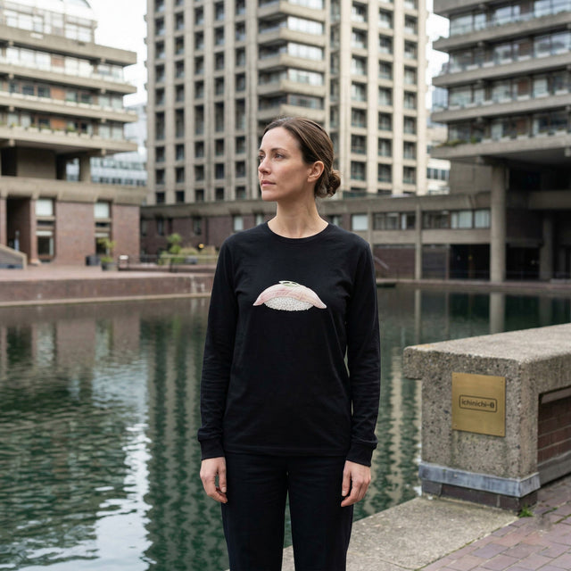 Woman wearing a black long-sleeve shirt with a design in an urban setting