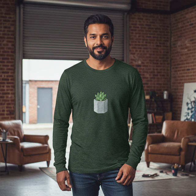 Man wearing a green long-sleeve shirt with a plant design in a room with brick walls and furniture.
