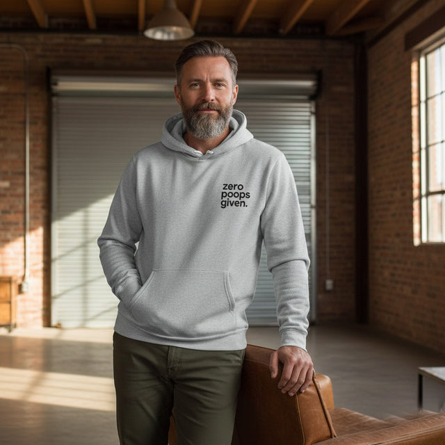 Man wearing a gray hoodie with 'zero poops given' text in a room with brick walls and large windows.
