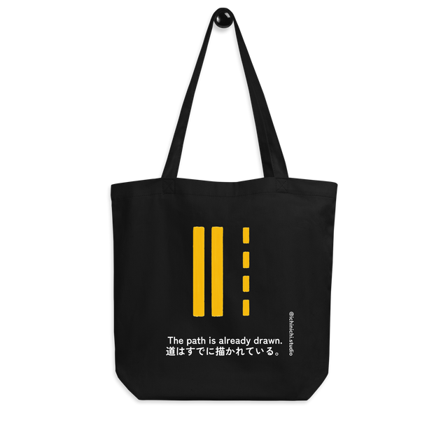 Minimal illustration of double yellow road lines with dashed markings on a tote bag design.
