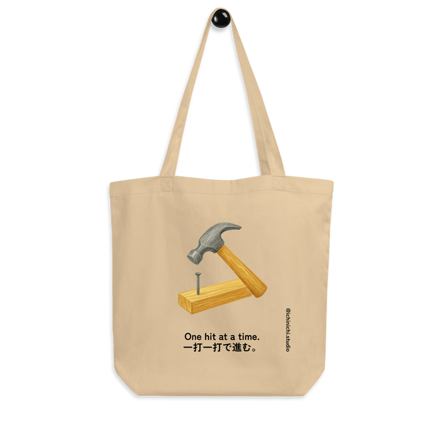 Minimalist Eco Tote Bag design featuring a hammer driving a nail into a 2x4 board.
